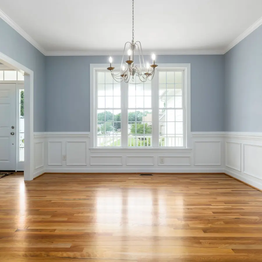 Empty dining room with white wainscoting, crown molding and hardwood floors