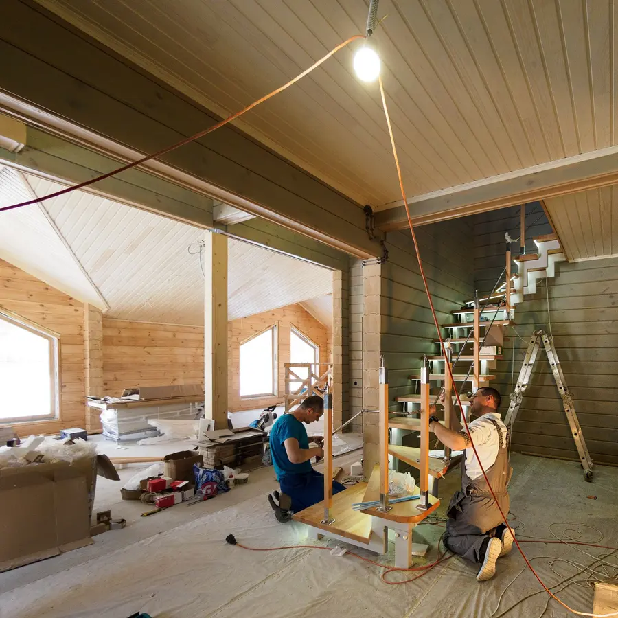 Carpenters building a wooden staircase inside a new home under construction